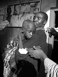 A starving 9-year-old boy is carried in to a feeding center in Congo